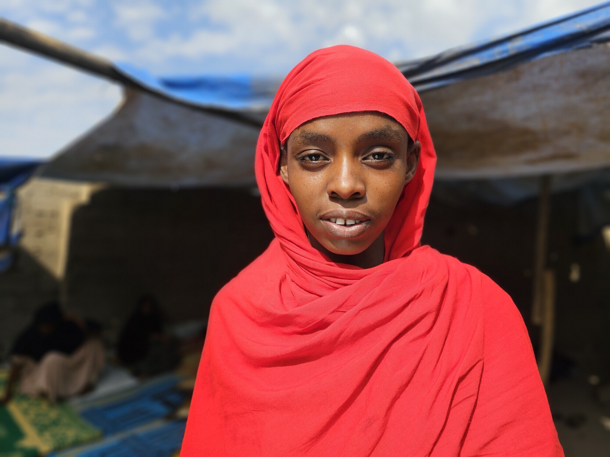 Portrett av en ung kvinne fra Etiopia som har på seg et rødt sjal.